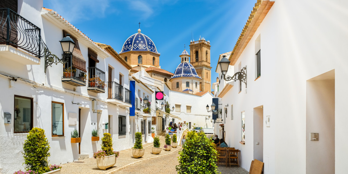 Calle de Altea con cielo azul brillante y el icónico techo azul de la iglesia en la Costa Blanca, España.