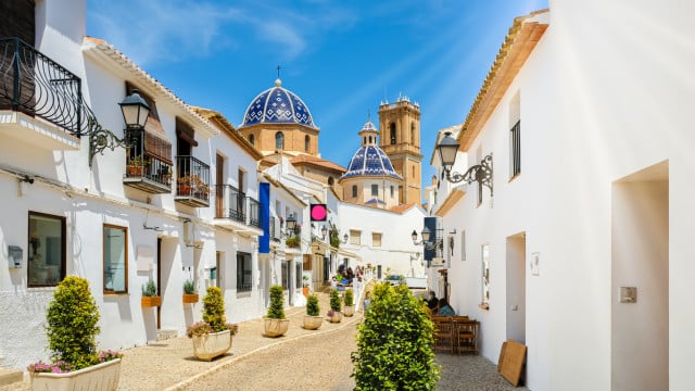 Calle de Altea con cielo azul brillante y el icónico techo azul de la iglesia en la Costa Blanca, España.