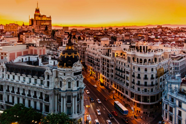 Vista panorámica de la Gran Vía de Madrid al atardecer, con el Edificio Metrópolis y la elegante arquitectura histórica de la ciudad.