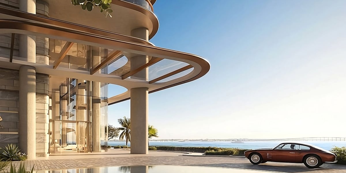 Hermosa foto del nuevo complejo de viviendas de marca donde se ve un auto antiguo aparcando en el lobby de la torre con vista al mar